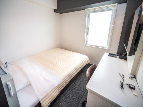 a bedroom with a bed and a desk and a window at Super Hotel Shinagawa Shinbanba in Tokyo