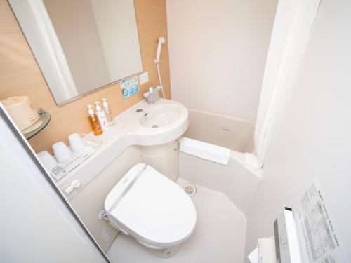 a white bathroom with a toilet and a sink at Super Hotel Shinagawa Shinbanba in Tokyo