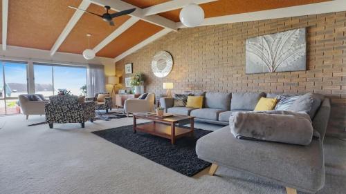 a living room with a couch and a brick wall at PiPis on Collins in Merimbula
