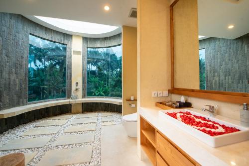a bathroom with a tub and a toilet and a sink at Triyana Resort and Glamping Carangsari Bali in Payangan