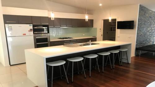a kitchen with a island with bar stools and a sink at Turaroo in Tura Beach