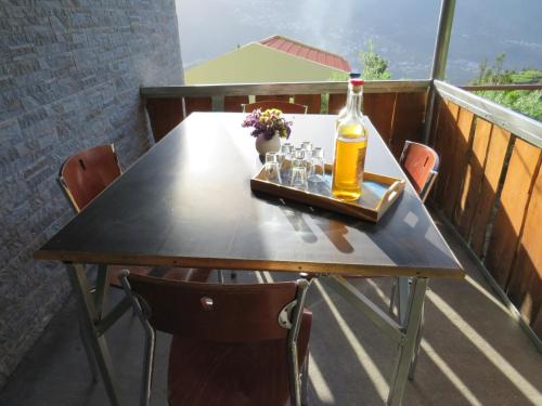 a table with a bottle and glasses on a balcony at Chalé Da Melaria in São Vicente