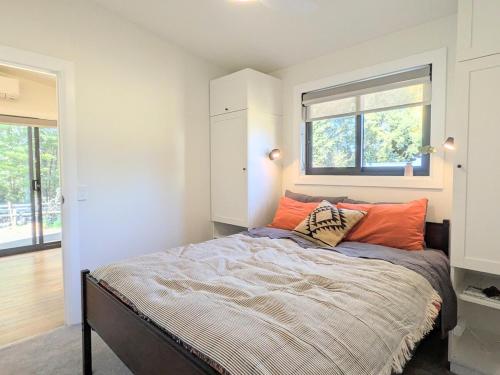 a bedroom with a bed with orange pillows on it at Elm's Deep Guest House in Berridale