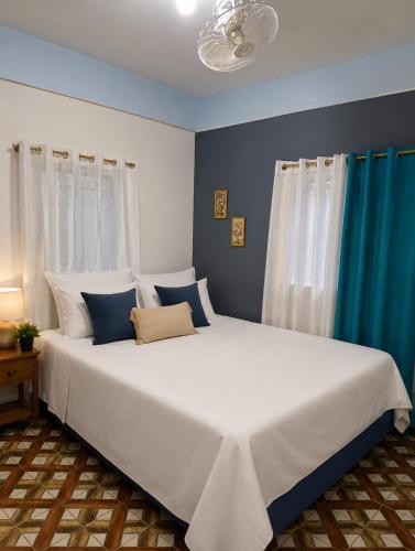 a bedroom with a large white bed with blue walls at spring house jarabacoa bbq ,piscina privada, Wi-Fi deco 10 huéspedes 3 baños, 2 aires A C 4 habitaciones in Jarabacoa