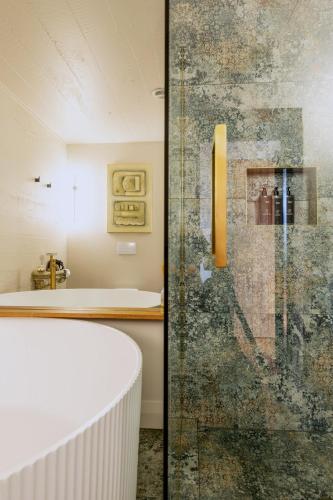 a bathroom with a tub and a glass shower door at The Advocate in Martinborough