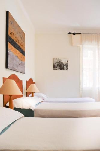 a white room with two beds and a window at Sanremo Apartments - Ortensia in Sanremo