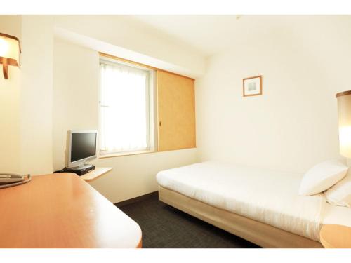a hotel room with a bed and a television at Smile Hotel Shiogama in Shiogama