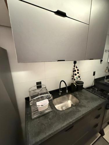 a kitchen counter with a sink and a microwave at Flat completo e aconchegante em Caruaru in Caruaru