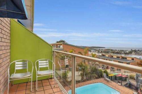 a balcony with two chairs and a swimming pool at Hydra 8 in Merimbula