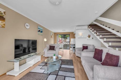 a living room with a couch and a staircase at Hydra 8 in Merimbula