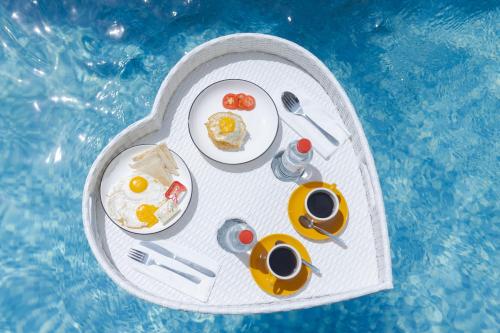 a white tray with food and drinks in a swimming pool at Nimis Villa in Canggu