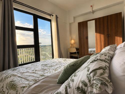 a bedroom with a bed and a large window at DG Coastal Comfort near Alona Beach - Pool, Gym and Play area in Dauis