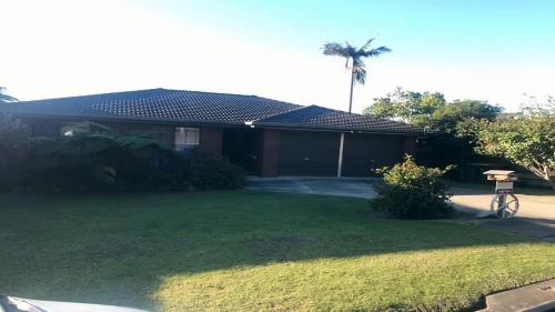 a house with a yard with a bike in front of it at Laura's Pambula Beach in Pambula Beach