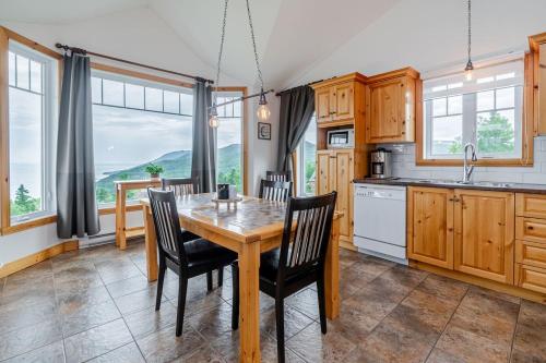 a kitchen with a wooden table and chairs at Panoramic View 2BR FP BBQ Terrace - Upper in Petite-Rivière-Saint-François