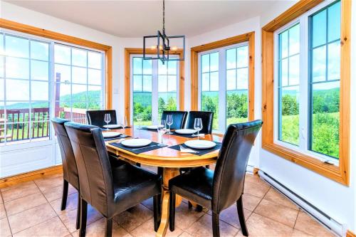 a dining room with a table and chairs and windows at Charlevoix 4BR Cottage Hot Tub & Game Room 12 in Petite-Rivière-Saint-François