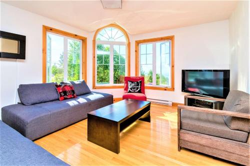 a living room with a couch and a tv at Charlevoix 4BR Cottage Hot Tub & Game Room 12 in Petite-Rivière-Saint-François