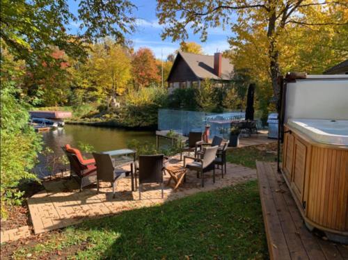 a patio with chairs and a table next to a river at Lakefront Chalet Hot Tub & Fire Pit Sleeps 6 in Saint-Raymond