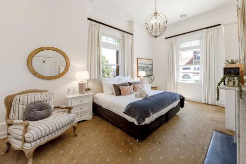 a bedroom with a bed and a chair and a mirror at QPO Queenscliff in Queenscliff