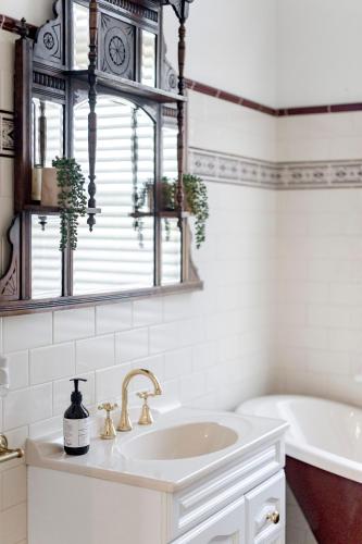 a white bathroom with a sink and a tub at QPO Queenscliff in Queenscliff