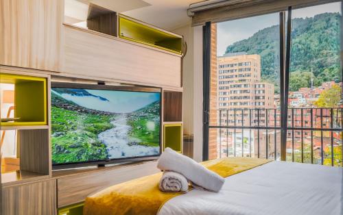 a bedroom with a large window and a large television at Espectacular Central Loft in Bogotá