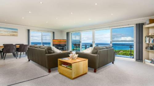 a living room with couches and a table with a view of the ocean at Quarterdeck 6 in Tura Beach