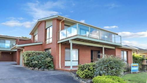 a red brick house with a glass balcony at SeaLeka 6 in Merimbula
