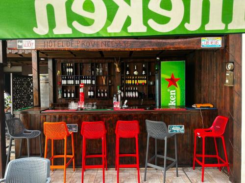 a bar with red chairs and bottles of wine at Hotel De Provence in El Jadida