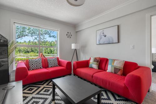 a living room with two red couches and a table at Vibrant Stylish, Cozy Waterfront Downtown in Calgary