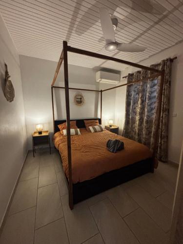 a bedroom with a canopy bed and two night stands at Maison avec piscine proche plage in Les Trois-Îlets