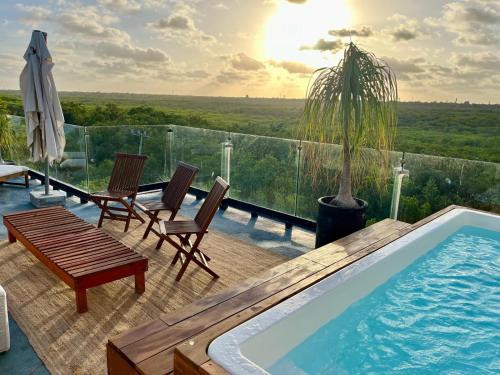 a swimming pool on a deck with chairs and a table at Beachfront 3BR Condo with Private Rooftop and lounge pool, Tankah Bay in Tulum