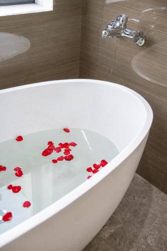 a bath tub with red rose petals on it at Hoàng Liên Hotel in Na Cốc