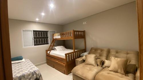 a bedroom with a bunk bed and a couch at Lara Country House in Guarulhos