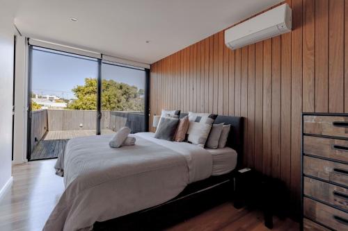 a bedroom with a large bed and a large window at Stella on Stevens in Queenscliff