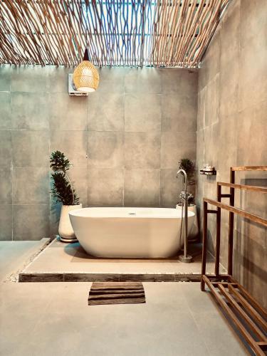 a bathroom with a tub and two potted plants at Home Dejavu in Gili Trawangan