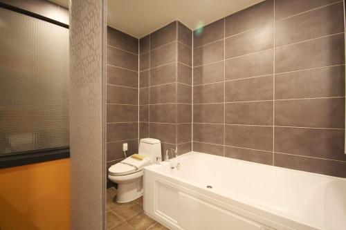 a bathroom with a white tub and a toilet at Iksan 4 Seasons Hotel in Iksan