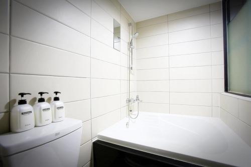 a white bathroom with a sink and a bath tub at Chuncheon Urbane Hotel in Chuncheon