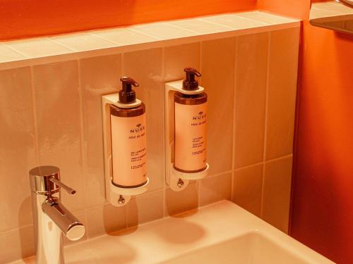 two bottles ofodorizers on a wall above a sink at Mercure Arles Centre Arenes in Arles