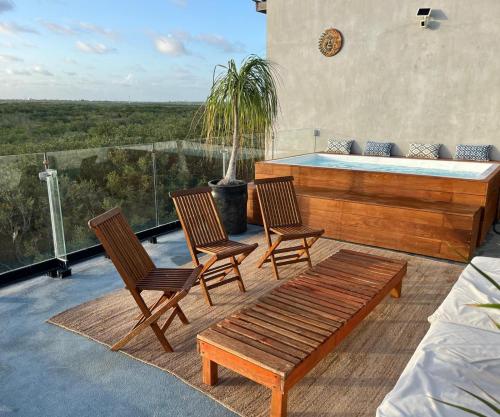 three chairs and a bench on a patio with a hot tub at Beachfront 3BR Condo with Private Rooftop and lounge pool, Tankah Bay in Tulum