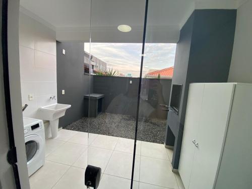 a bathroom with a washing machine and a washer and dryer at Casa nova e ampla, completa para sua hospedagem in Joinville