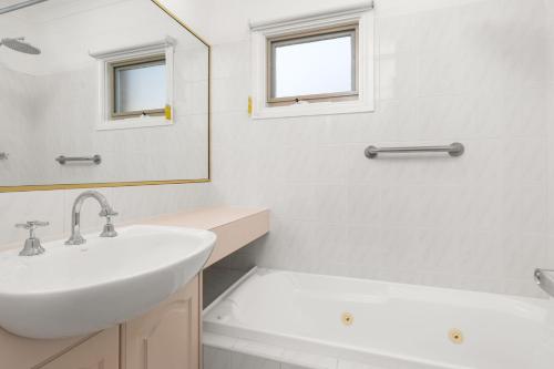 a white bathroom with a sink and a mirror at Sunset Drift Edithvale Steps to Beach in Edithvale