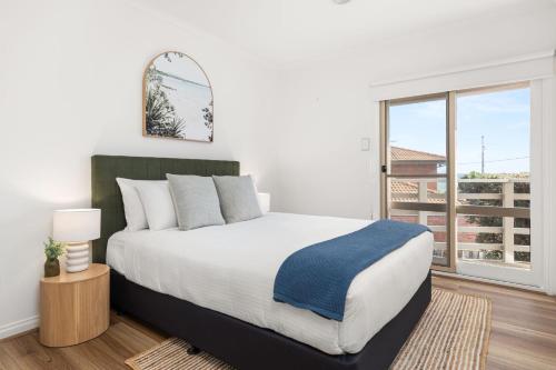 a bedroom with a large bed and a large window at Sunset Drift Edithvale Steps to Beach in Edithvale