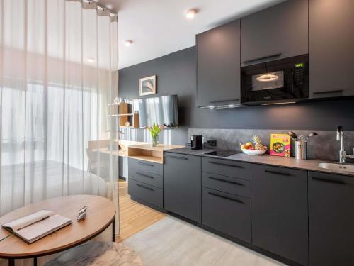 a kitchen with gray cabinets and a wooden table at Aparthotel Adagio Stuttgart NeckarPark in Stuttgart
