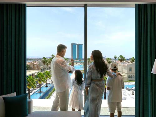 a family looking out the window of a hotel at Rixos Obhur Jeddah Resort & Villas - All-Inclusive in Jeddah