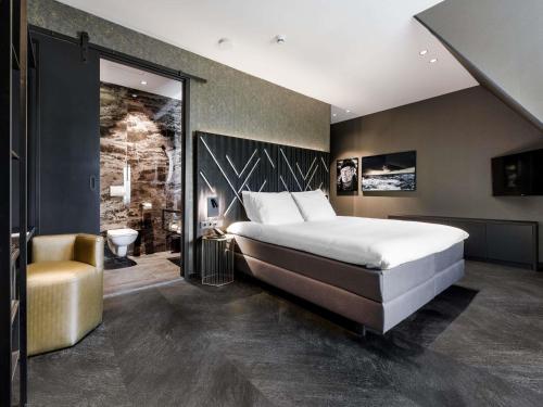 a bedroom with a large white bed and a chair at Le Marin Hotel Rotterdam City - Handwritten Collection in Rotterdam