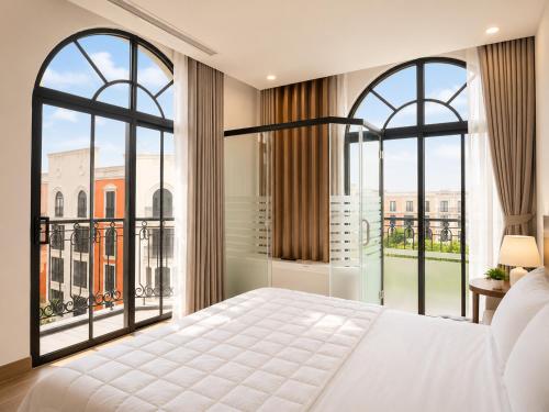 ein Schlafzimmer mit einem großen Bett und großen Fenstern in der Unterkunft Sun Hotel Sam Son in Sầm Sơn