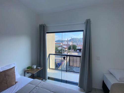 a bedroom with a bed and a large window at Casa nova e ampla, completa para sua hospedagem in Joinville