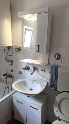 a white bathroom with a sink and a toilet at Petronas Apartment in Niš