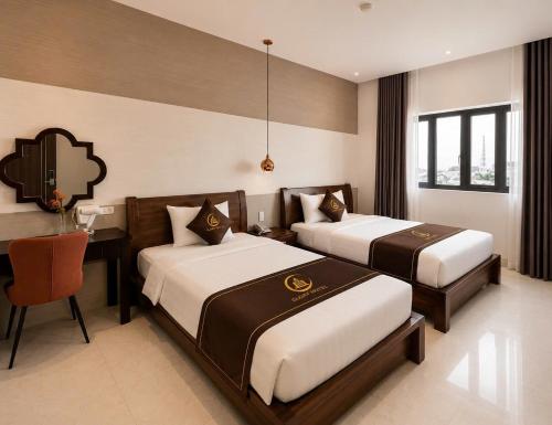 a bedroom with two beds and a table and a desk at Glory Hotel in Can Tho