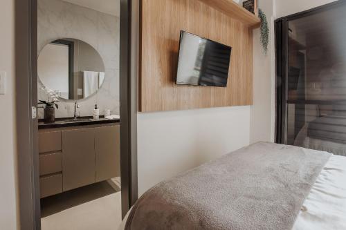 a bedroom with a bed and a tv on the wall at Actual House in Uberlândia