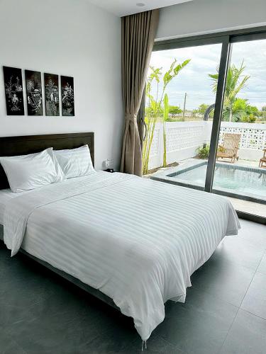 a bedroom with a large white bed and a balcony at LAA Maison in Hoi An